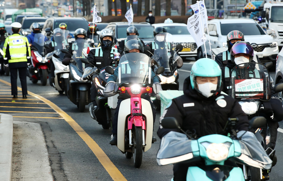 Delivery workers that are members of the umbrella Korean Confederation of Trade Unions ride in convoy near the Baedal Minjok headquarters in Songpa District, southern Seoul on Thursday, calling on the company to raise delivery fees and introduce surcharges based on the distance they need to travel to pick-up food. [YONHAP]