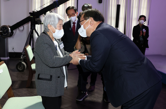 Prime Minister Kim Boo-kyum, right, clasps the hands of Jeon Chae-ryeon, a first-generation ethnic Korean who returned home last month from Sakhalin, an island in the Russian Far East, as part of the Korean government program to return the first-generation ethnic Koreans, at a welcoming ceremony at the Jeongdong 1928 Art Center in central Seoul on Thursday. [YONHAP]