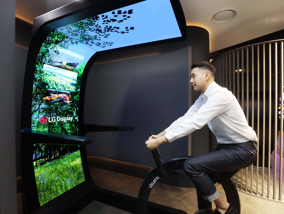 A model demonstrates LG Display's Virtual Ride that merges a stationary bike with a curved OLED Display. [LG DISPLAY]