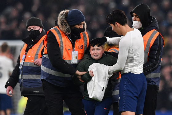 Tottenham Hotspur's Son Heung-min gives his shirt to a young pitch invader after a Carabao Cup quarterfinal football match against West Ham at Tottenham Hotspur Stadium in London on Wednesday. Son comforted the young fan, who had burst into tears after being intercepted by security guards while seemingly trying to reach the Korean striker. [AFP/YONHAP]