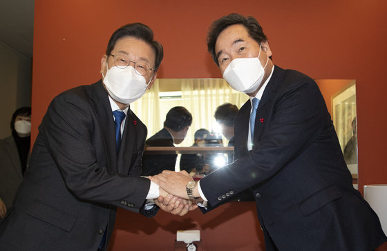 The ruling Democratic Party’s presidential candidate Lee Jae-myung, left, shakes hands with former Prime Minister Lee Nak-yon at a luncheon meeting at a restaurant in central Seoul Thursday to discuss working together on the election campaign. [JOINT PRESS CORPS] 