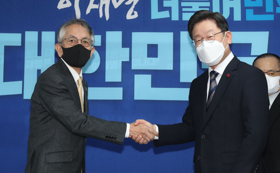Ruling Democratic Party (DP) presidential candidate Lee Jae-myung, right, shakes hands with Japanese Ambassador Koichi Aiboshi, left, at the DP headquarters in western Seoul on Monday. [KIM KYUNG-ROK]