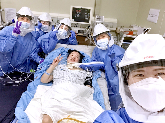 Kim Mi-na, center, celebrates with the medical team in July after waking up after undergoing extracorporeal membrane oxygenation (ECMO) treatment for 17 days at Seoul National University Hospital. She was the first pregnant woman infected with Covid-19 to get ECMO treatment in Korea. [KIM MI-NA]
