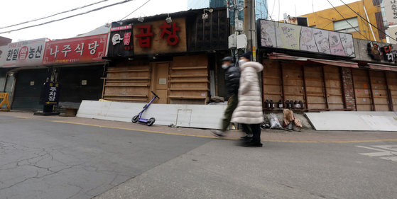 Pedestrians walk by closed restaurants in Sinchon, western Seoul, on Tuesday. Korea's industrial landscape dramatically changed over the past five years as manufacturing, retail and service businesses shrunk. [NEWS1]