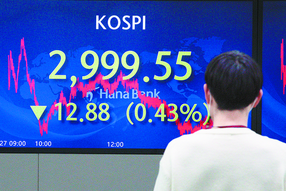  An investor looks at an electronic board in a dealing room at Hana Bank in Seoul on Dec. 27, when the Kospi fell below the 3,000 mark, a 0.43 percent drop from the day before. [NEWS1]