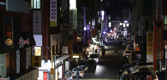 Shop owners in a commercial district in Gwangjin District, eastern Seoul, on Dec. 27 turn lights off for an hour in protest of the government's Covid-19 related policies, including social distancing regulations and support. [YONHAP] 