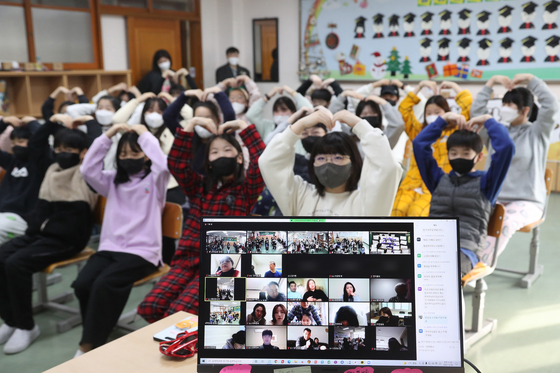 Sixth graders attend their graduation ceremony at Sinyeong Elementary School in Suwon, Gyeonggi, on Thursday while their parents watch online. Due to fears of spreading Covid-19 infections, the school held the graduation ceremony two months early, on the last day of holding classes in-person, so they would not have to get together again later. [NEWS1]