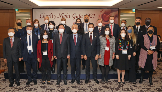 Kim Jong-hoon, chairman of the board of directors of SK Innovation, fifth from front left, Cheong Chul-gun, CEO of the Korea JoongAng Daily, fourth from front left, and ambassadors and spouses partake in the 2021 Charity Night Gala, an evening concert with winners of the 5th Great Music Festival hosted by the SK Innovation and the Korea JoongAng Daily, at the Lotte Hotel Seoul on Tuesday. [PARK SANG-MOON]