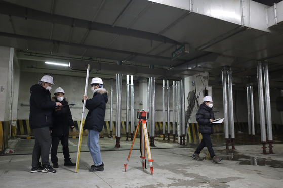 Engineers inspect a building in Madu-dong in Goyang, Gyeonggi, on Monday after one of its basement columns was damaged on Dec. 31. [GOYANG CITY GOVERNMENT]