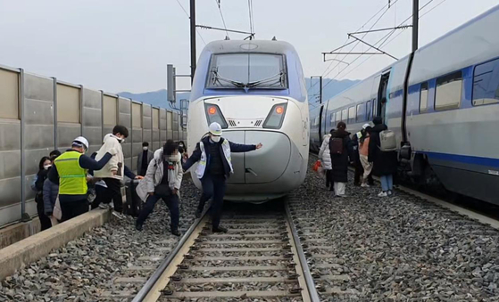 Passengers exit the derailed KTX train, which was hit by an object that fell from the ceiling of the Yeongdong Tunnel in North Chungcheong around 11:58 a.m. on Wednesday, to board a train arranged to pick them up. [YONHAP]