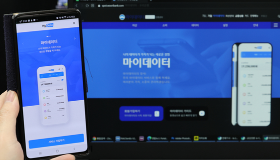A user shows Woori Bank's MyData application and website on Wednesday, the first day companies were approved to start such services by the Financial Services Commission. MyData is a government-led project that allows businesses to access user information upon their consent. Woori Bank's will allow its users to check all of their financial information such as savings, loans and insurance payments in one app. [YONHAP]