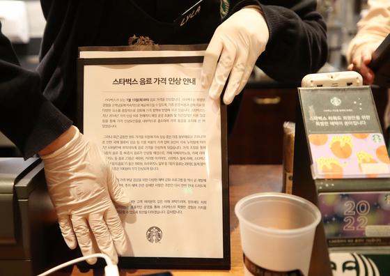 A Starbucks barista on Friday puts up a notice saying the coffee chain will raise prices starting Jan. 13. [NEWS1]