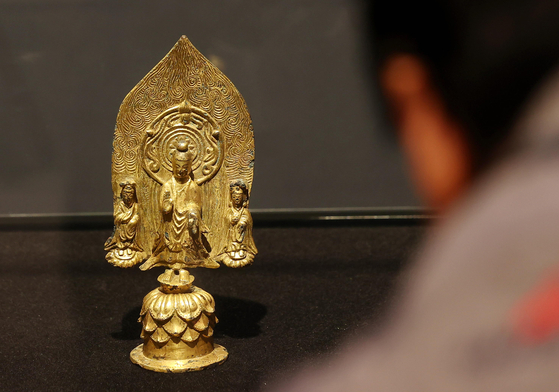A local reporter looks at the Gilt-bronze Standing Buddha Triad with Inscription of "Gyemi Year" at K Auction in southern Seoul on Monday. [YONHAP]