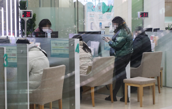 Customers do banking at a branch in Seoul on Jan. 14. [YONHAP]
