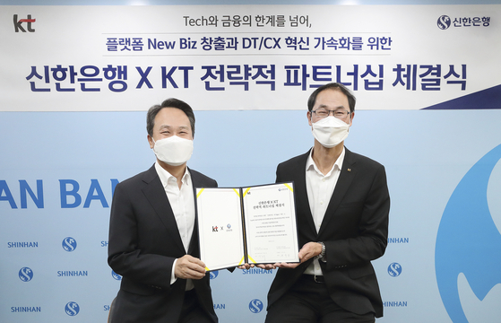 Jin Ok-dong, Shinhan Bank CEO, left, and Park Jong-ook, President of KT, at a strategic partnership ceremony held at Shinhan Bank&#39;s main branch in central Seoul on Monday. [KT]  