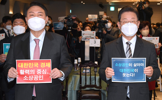 Opposition People Power Party presidential candidate Yoon Suk-yeol, left, and Democratic Party presidential candidate Lee Jae-myung pose for a commemorative photo at an event supporting small businesses in Yeouido, western Seoul, Tuesday. [JOINT PRESS CORPS] 