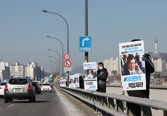 Workers on strike hold signs in protest at the Banpo Bridge in southern Seoul on Tuesday. [YONHAP]