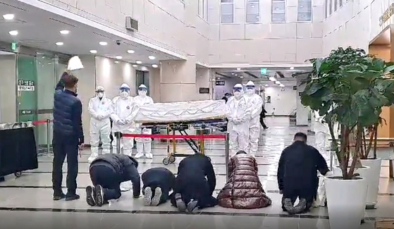 The family of a patient who died from Covid-19 bows in the direction of the coffin held by staff at a cremation center in Gyeonggi, Gyeonggi, in December to say their final goodbye. [KOREA FUNERAL ASSOCIATION]