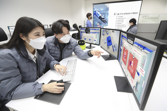 KT staffers work on the testbed for automated industrial robots using the 5G network for the Korea Institute for Robot Industry Advancement (Kiria). [KT]