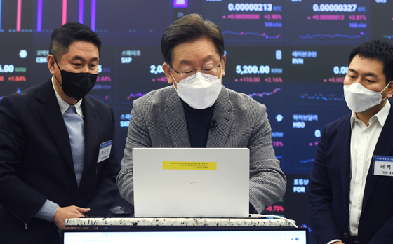 Democratic Party presidential candidate Lee Jae-myung, center, demonstrates how to issue a non-fungible token (NFT) at the Upbit lounge in Gangnam District, southern Seoul, on Wednesday. [YONHAP]