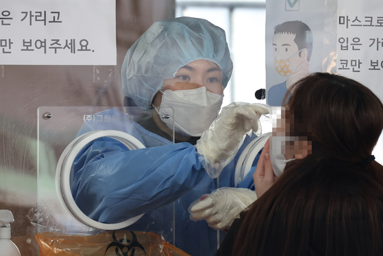 A woman undergoes a polymerase chain reaction (PCR) test for Covid-19 at a testing center near Seoul Station on Friday. The PCR tests will no longer be available for everyone in regions where Omicron cases have grown dominant, including Gwangju and Pyeongtaek, Gyeonggi, starting Wednesday, as health authorities try to adjust the testing and treatment system to keep up with the speed of Omicron infections. The use of self-testing kits and rapid antigen tests will be added as alternative options in getting tested. [YONHAP]