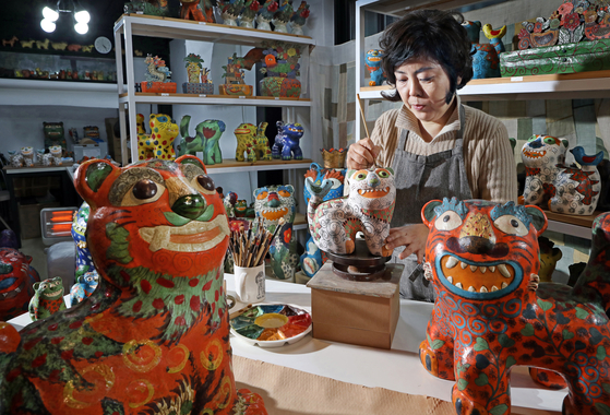 Artist Jang Mee-kyung, known for her ceramic tiger statues, is in the final stage of coloring her tigers at her kkokdu [a traditional wooden doll] pottery studio in Seongbuk District, northern Seoul. [PARK SANG-MOON]