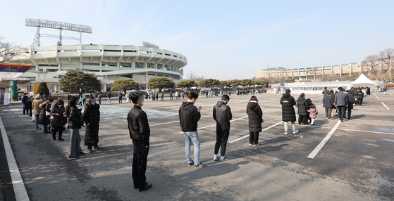 People line up at a Covid-19 testing site at the Jamsil Sports Complex in Songpa District, southern Seoul, Wednesday, as the country’s daily cases soared above 13,000 cases, the highest since the outbreak of the pandemic. [NEWS1]