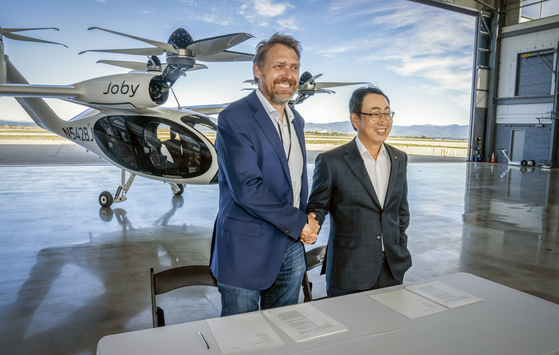 JoeBen Bevirt (left), founder and CEO of Joby Aviation, and SKT CEO Ryu Young-sang shake hands after signing an agreement at Joby Aviation’s manufacturing plant in Marina, California to develop emissions-free air taxis for Korea. [SK TELECOM]