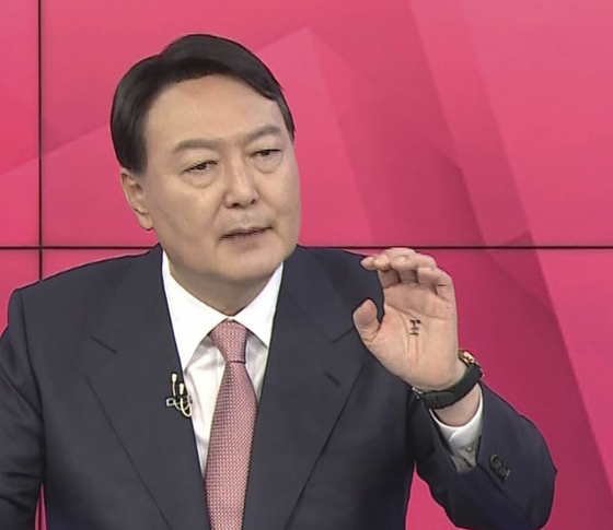 Presidential election candidate Yoon Suk-yeol speaks during a televised debate on MBN on Oct. 1. On his palm is written a Chinese character for "king." [YONHAP] 