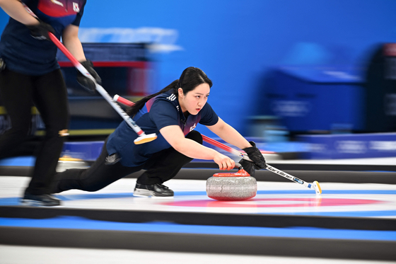 Kim Kyeong-ae curls the stone during a women's round robin game against China at the National Aquatics Centre in Beijing on Sunday. [AFP/YONHAP]
