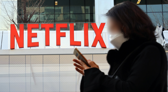 A passerby walks past a Netflix logo set up at Coex in Samseong-dong, southern Seoul, last December to promote the release of "Hellbound" (2021). [YONHAP] 
