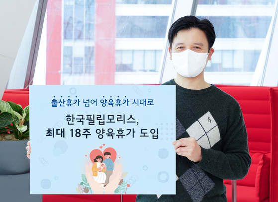 An employee at Philip Morris Korea holds a banner promoting a new parental leave policy at the companay's office in Yeouido, western Seoul. [PHILIP MORRIS KOREA]