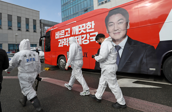Police officers and National Forensic Service staffers examine a chartered bus in Cheonan, South Chungcheong, after two workers on the campaign of the People’s Party presidential candidate Ahn Cheol-soo were found dead inside it the previous day. [YONHAP]