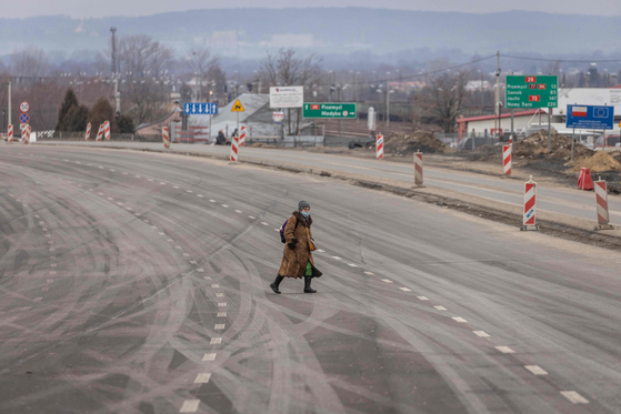 A woman crosses a road in Medyka in southeast Poland, close to the border with Ukraine on Tuesday. [AFP/YONHAP]