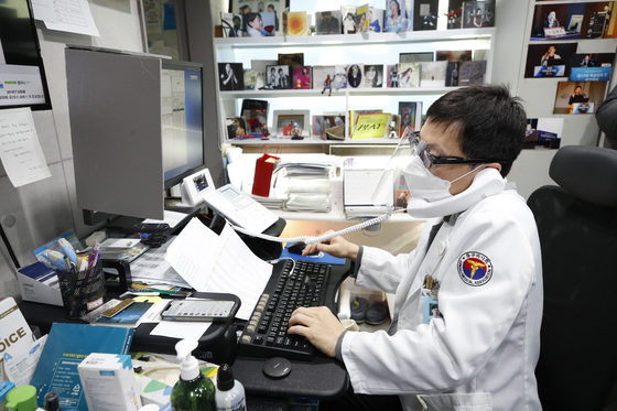 A doctor at an ears, nose and throat hospital in Jung District, central Seoul, treats a Covid-19 patient by phone Thursday as the country operates an at-home treatment system to manage the surge in Omicron cases. [NEWS1]