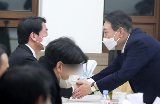 Yoon Suk-yeol, presidential candidate for the People Power Party, right, expresses condolences to Ahn Cheol-soo, candidate of the People's Party, on Wednesday night.  [YONHAP] 
