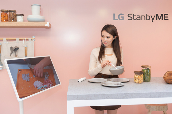 A model watches the StanbyMe screen while cooking. [LG ELECTRONICS]