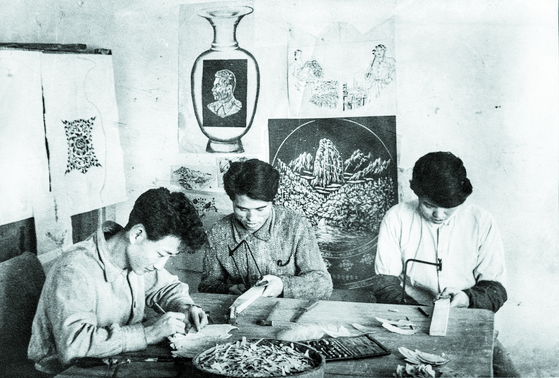 A photograph of North Korean craftsmen working on the gifts Kim Il Sung gave to Stalin, which was included in the catalogue booklet. [KIM HYUN-DONG]
