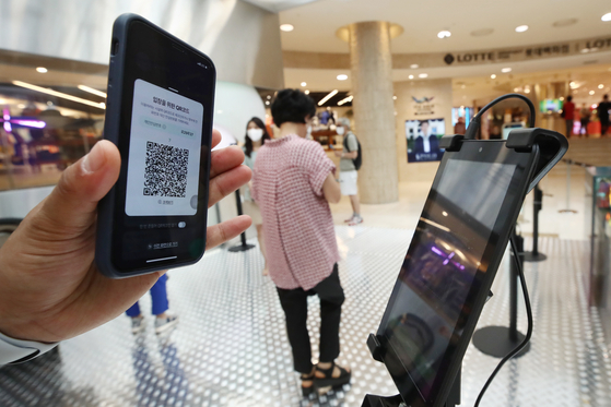 A visitor to Lotte Department Store's main branch in central Seoul checks in using a QR code. [YONHAP]