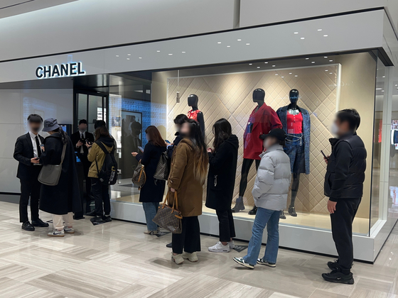 People wait in line for Chanel after the department store opens at 10 a.m. Although lining up early in the morning gives people better chances of purchasing Chanel bags, some even line up later in the afternoon just in case bags are stocked later. [LEE TAE-HEE]