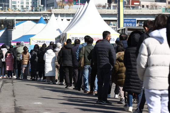 People wait in line to take a Covid-19 test at a temporary screening center at Seoul Station on Sunday. [YONHAP]