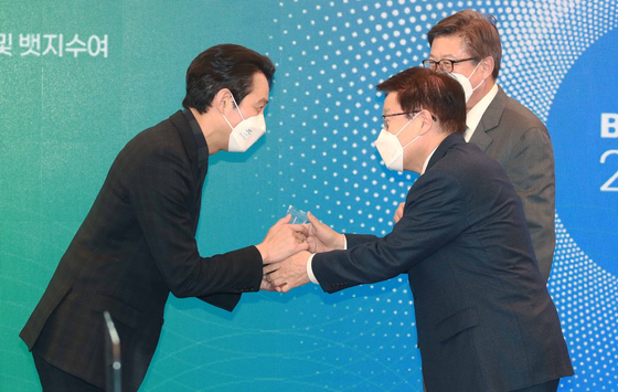 'Squid Game' actor Lee Jung-jae, left, greeted by the Bid Committee for World Expo 2030 Busan chairman Kim Young-ju, center, and Busan mayor Park Heong-joon at Lotte Hotel in December 2021. Lee was appointed as the first celebrity spokesperson for the Busan World Expo 2030. [THE BID COMMITTEE FOR WORLD EXPO 2030 BUSAN] 