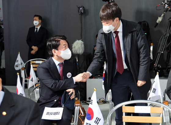 Ahn Cheol-soo, left, presidential candidate of the People's Party, shakes hands with People Power Party Chairman Lee Jun-seok at a March 1st Independence Movement ceremony at the National Memorial of the Korean Provisional Government in central Seoul Tuesday. [YONHAP]