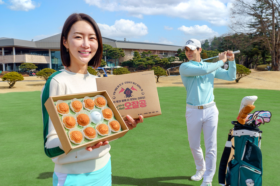A model holds up a golf ball-themed bakery package on a golf course. Shinsegae Food introduced golf-themed bakery items on Wednesday, as the golf season begins in March in Korea. [YONHAP]