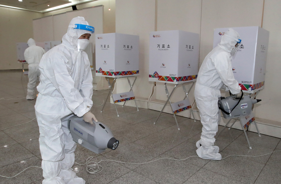Sanitation workers disinfect a polling station set up for early voting in the March 9 presidential election at a convention center in Gwangju on Thursday, one day before early voting begins. [YONHAP]