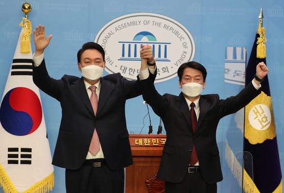 Yoon Suk-yeol, left, presidential candidate of the main opposition People Power Party, and Ahn Cheol-soo of the minor opposition People's Party, hold a joint press conference at the National Assembly in western Seoul Thursday. After agreeing on a merger in an overnight meeting, Ahn announced he will back Yoon as the unified opposition candidate. [NEWS1]