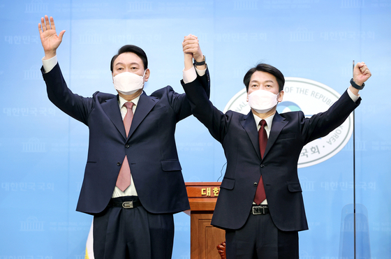 Yoon Suk-yeol, left, presidential candidate for the main opposition People Power Party, and Ahn Cheol-soo of the minor opposition People's Party, hold a joint press conference at the National Assembly in western Seoul Thursday. After agreeing on an electoral alliance in an overnight meeting, Ahn announced he would back Yoon as the unified opposition candidate. [JOINT PRESS CORPS] 