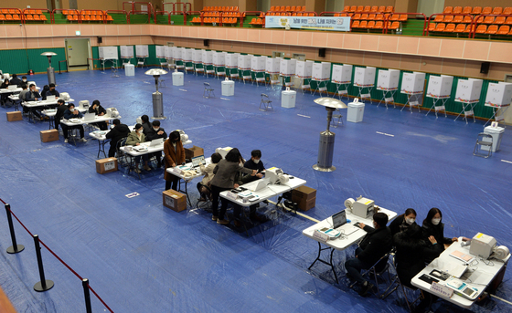 Officials from the National Election Commission examine electronic ballot-tallying devices and voting booths set up in a gymnasium in Nonsan, South Chungcheong, on Thursday, a day before early voting begins. [KIM SEONG-TAE]