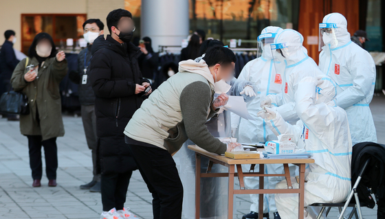 Staff check the identities of Covid-19 patients at an early voting polling station for the March 9 presidential election at Seoul Station in central Seoul, on Saturday. [NEWS1]