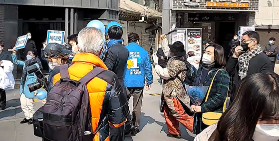 A 70-year-old YouTuber, center right, attacks Song Young-gil, chief of the ruling Democratic Party (DP), center, with a hammer during a DP election campaign rally in Sinchon in Seodaemun District, western Seoul, around noon Monday. [NEWS1]